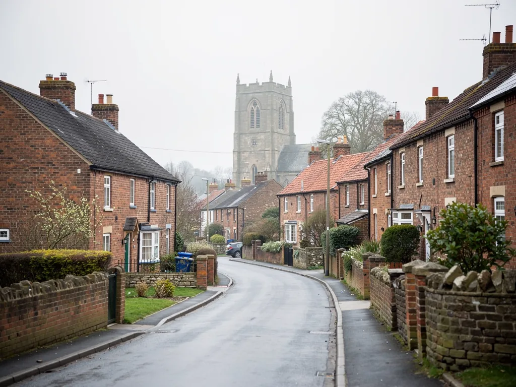 A village street of brick houses near York with a church tower beyond