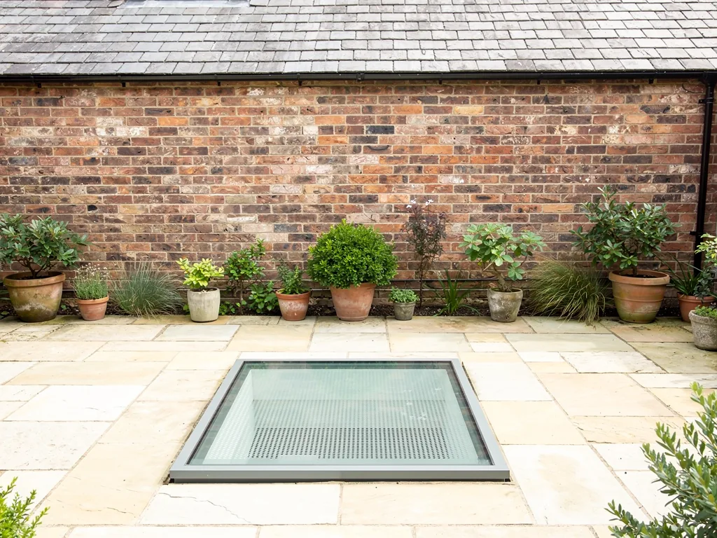 A walk-on glass rooflight set flush into a paved courtyard